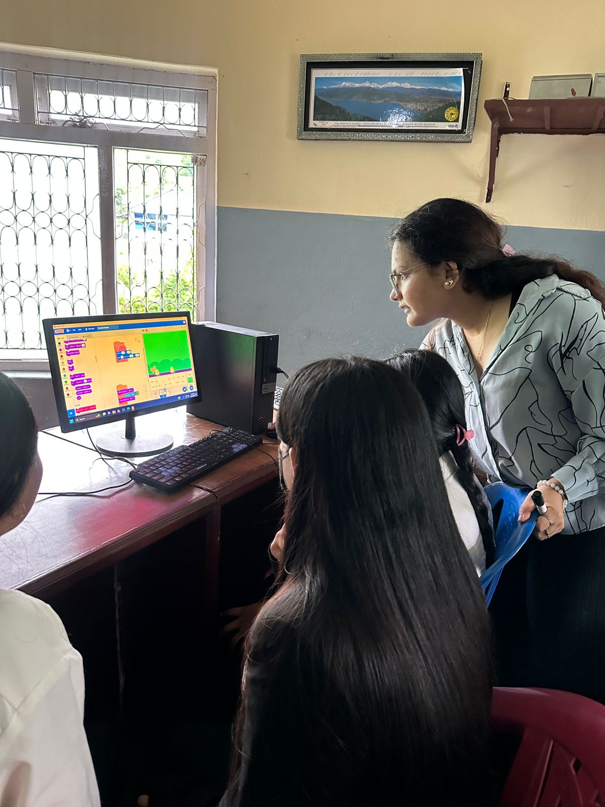 Fellows teaching students how to use Scratch in a school computer lab